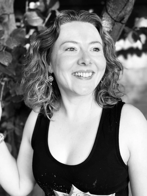 Sarah Locke standing in front of a tree in a black and white image